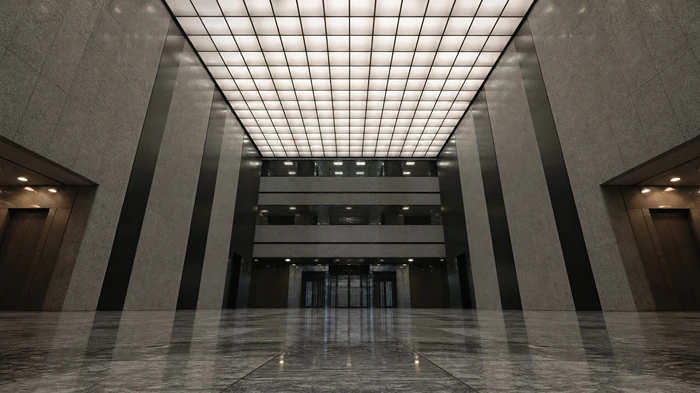 A wide-angle, low-perspective shot of a symmetrical and empty modern office lobby, emphasizing scale and centralized composition.